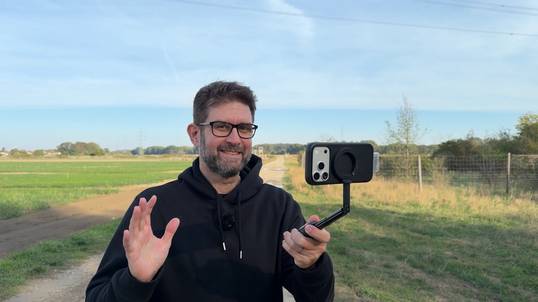 Christian Eggbauer outdoors, holding a smartphone filming setup.